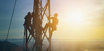 Two people working on telecommunications tower