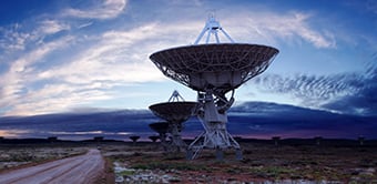 Satellites near dirt road pointed skyward at sunset