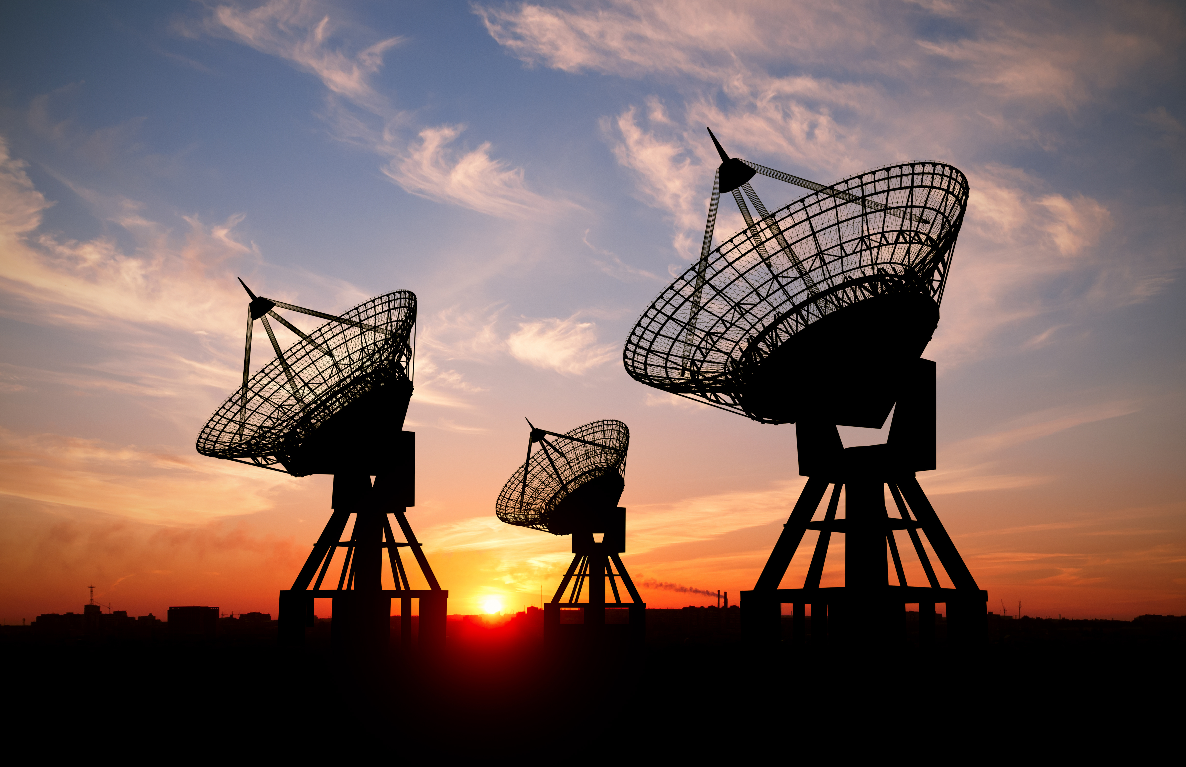 3 Satellites point northwest silhouetted by a sunset.